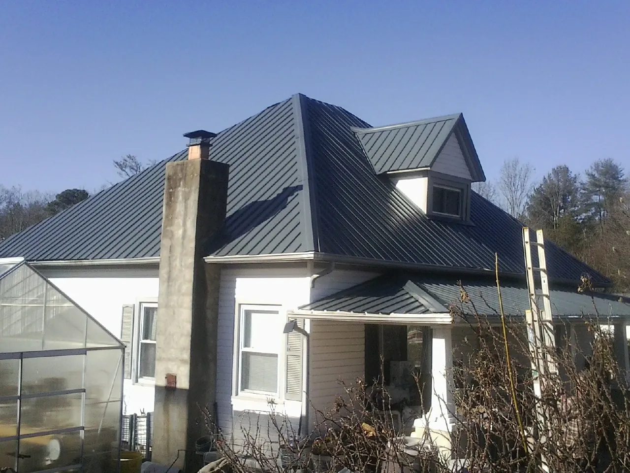 Dark blue standing seam metal roof on a white farmhouse with dormer — Slate & Tile Roof Repair by Roofing Brothers in Herrin