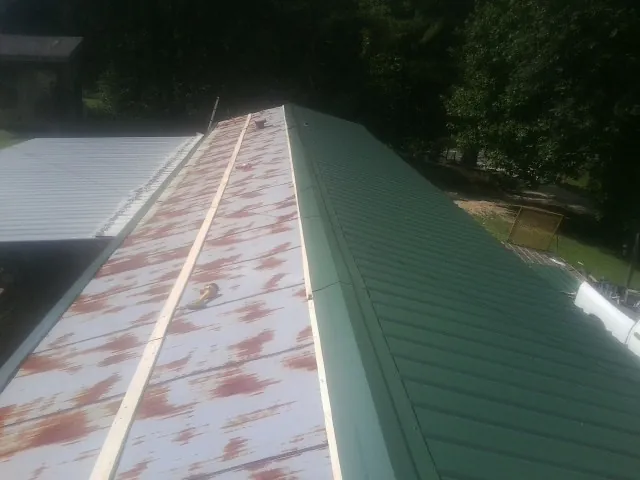 Old rusted panels beside newly installed green metal roofing — Wind Damage Roof Repair by Roofing Brothers in Herrin