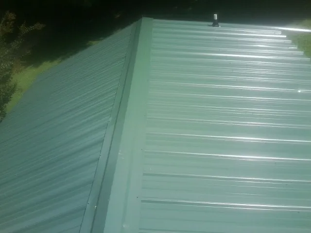 New green metal panels meeting at the ridge of a roof — Flat Roof Repair work by our crew in Herrin