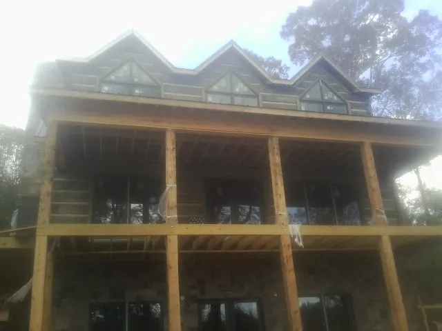Dormers and porch framing on a large log home under construction — Roof Coating work by our crew in Herrin