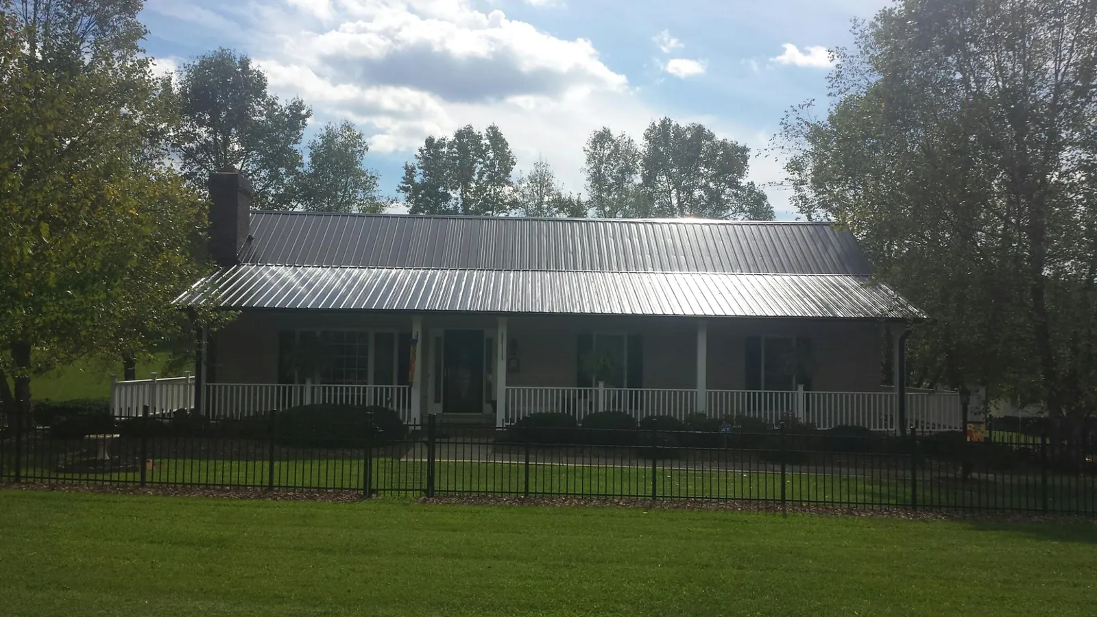 Gray metal roof on a brick ranch with a full width front porch — Gutter Guard Installation work by our crew in Herrin