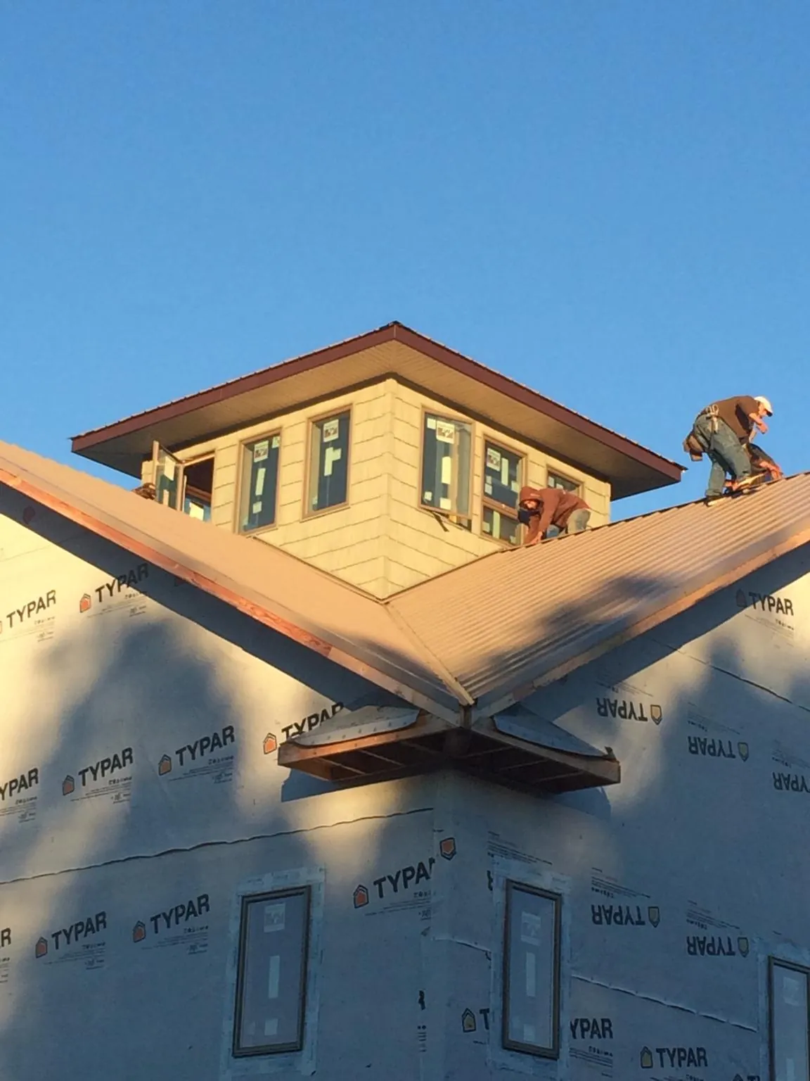 Roofers working around a rooftop cupola on a new metal roof at sunset — Roof Waterproofing in Herrin by Roofing Brothers